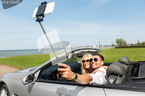 Image of happy couple in car taking selfie by smartphone