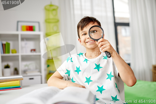 Image of happy boy looking through magnifier at home