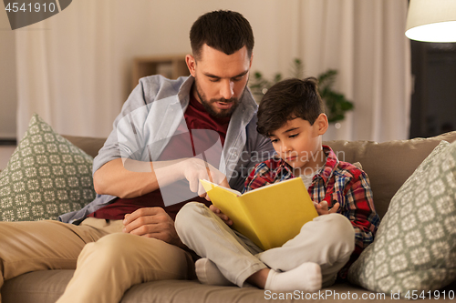 Image of father and son reading book sofa at home
