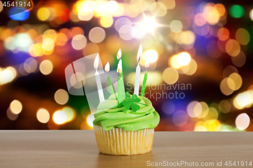 Image of green cupcake with six burning candles on table