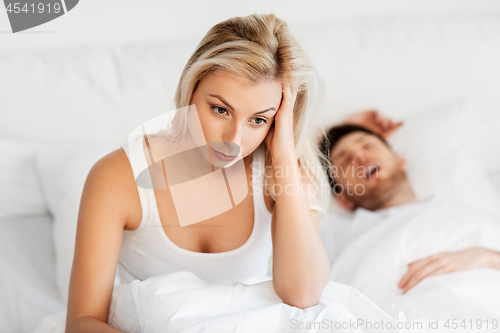 Image of unhappy woman in bed with snoring sleeping man