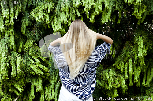 Image of Beautiful young woman standing in the forest against fir trees.