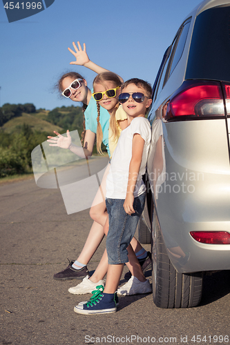 Image of Happy brother and his two sisters are standing near the car at t