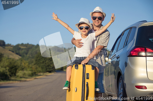 Image of Happy father and son standing near the car at the day time.