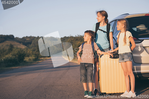 Image of Happy brother and his two sisters are standing near the car at t