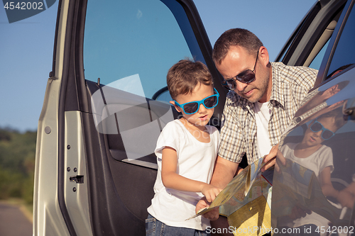 Image of Happy father and son standing near the car at the day time.