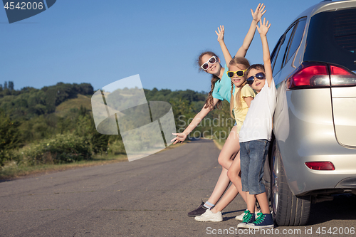 Image of Happy brother and his two sisters are standing near the car at t