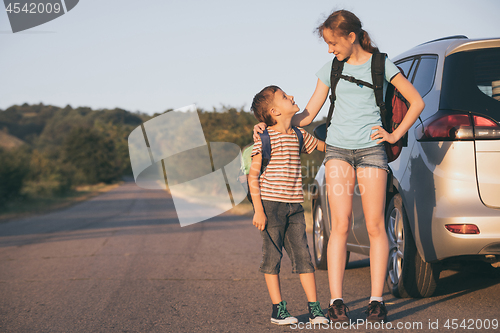 Image of Happy brother and his  sister are standing near the car at the d