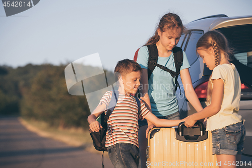 Image of Happy brother and his two sisters are standing near the car at t