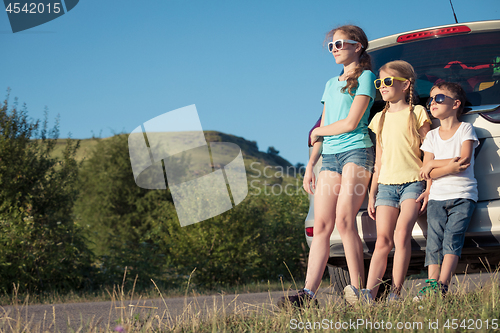 Image of Happy brother and his two sisters are standing near the car at t