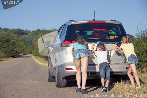 Image of Happy brother and his two sisters are standing near the car at t