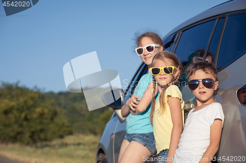 Image of Happy brother and his two sisters are standing near the car at t