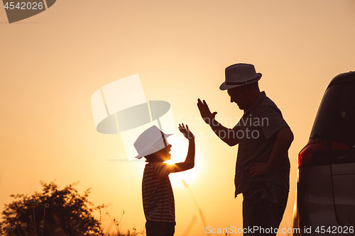 Image of Father and son playing in the park at the sunset time.