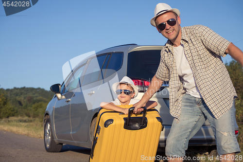 Image of Happy father and son standing near the car at the day time.