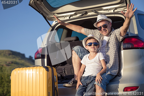 Image of Happy father and son standing near the car at the day time.