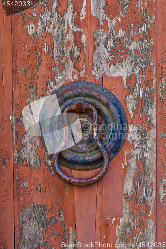 Image of Italian door knocker on old wooden red background.