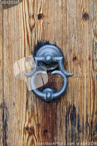 Image of Italian door knocker on old wooden brown background.