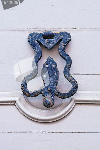 Image of Italian door knocker on wooden painted white door.