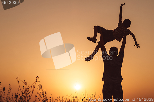 Image of Father and son playing in the park at the sunset time.