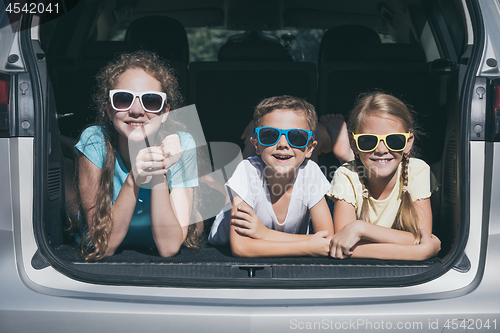 Image of Happy brother and his two sisters are sitting in the car at the 