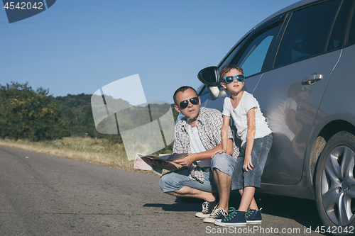 Image of Happy father and son standing near the car at the day time.