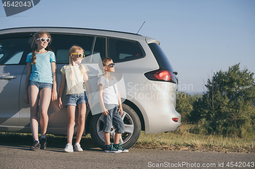 Image of Happy brother and his two sisters are standing near the car at t