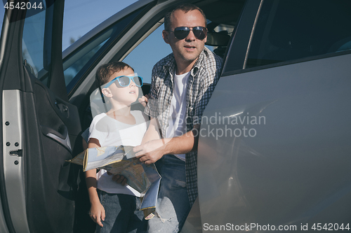 Image of Happy father and son standing near the car at the day time.