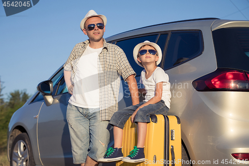 Image of Happy father and son standing near the car at the day time.