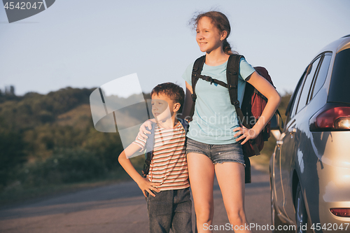 Image of Happy brother and his  sister are standing near the car at the d