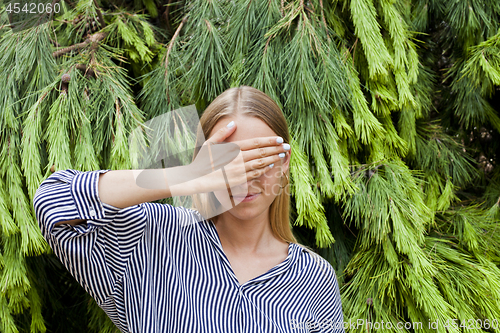 Image of Woman wearing elegant clothes hiding her face standing in the fo