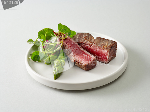 Image of Plate of beef wagyu steak meat with herbs and asparagus