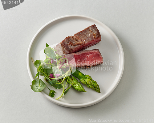 Image of Plate of beef wagyu steak meat with herbs and asparagus