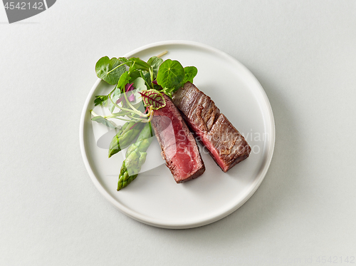 Image of Plate of beef wagyu steak meat with herbs and asparagus