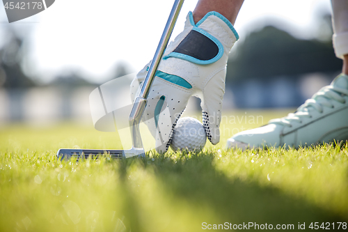 Image of Hand in glove placing golf ball on tee