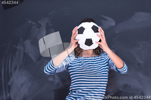 Image of woman holding a soccer ball in front of chalk drawing board