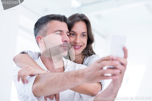 Image of happy couple using mobile phone at home