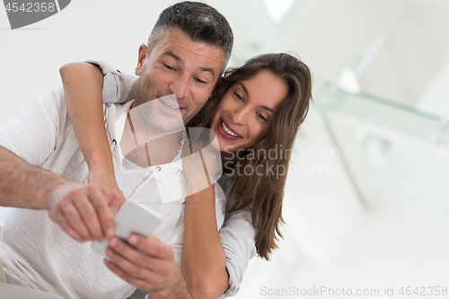 Image of happy couple using mobile phone at home