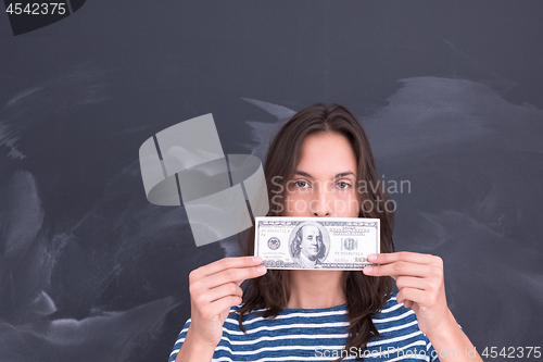 Image of woman holding a banknote in front of chalk drawing board