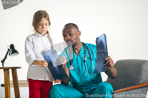 Image of Young african male pediatrician explaining X-ray to child