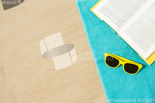 Image of sunglasses and book on beach towel on sand