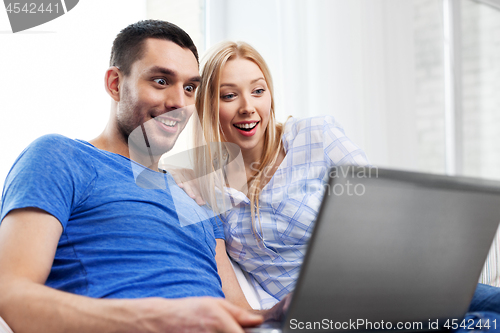 Image of happy couple with laptop computer at home