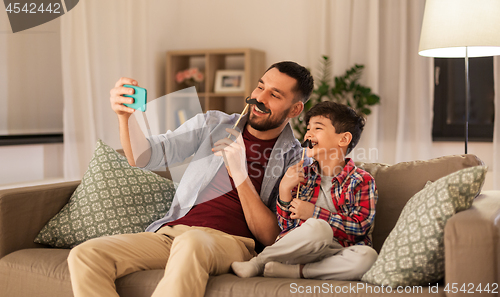 Image of father and son taking selfie at home