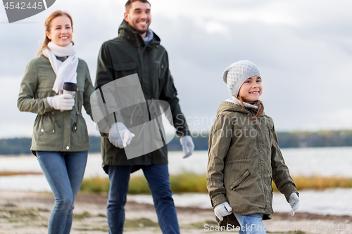 Image of happy family walking along autumn beach