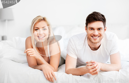 Image of happy couple lying in bed at home