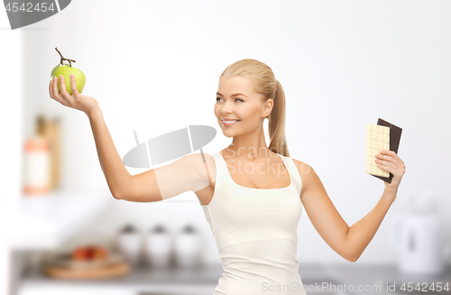 Image of woman choosing green apple instead of chocolate