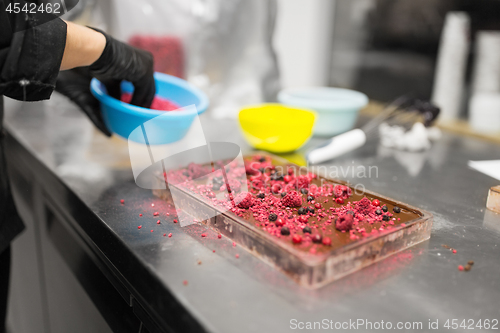 Image of confectioner makes chocolate dessert at sweet-shop