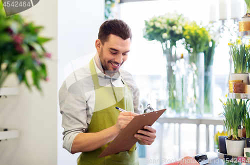 Image of florist man with clipboard at flower shop counter