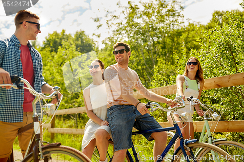 Image of happy friends riding fixed gear bicycles in summer