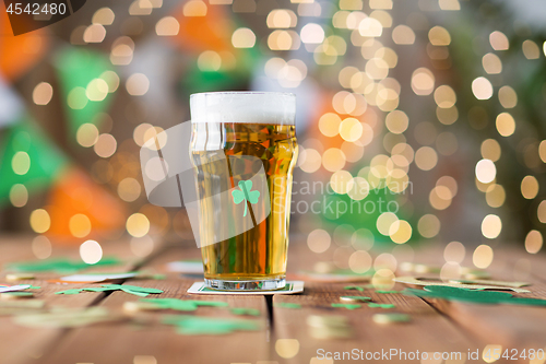 Image of glass of beer with shamrock and coins on table