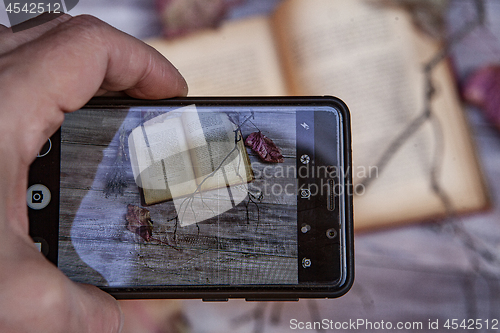 Image of Book And Autumn Leaves Through Smartphone